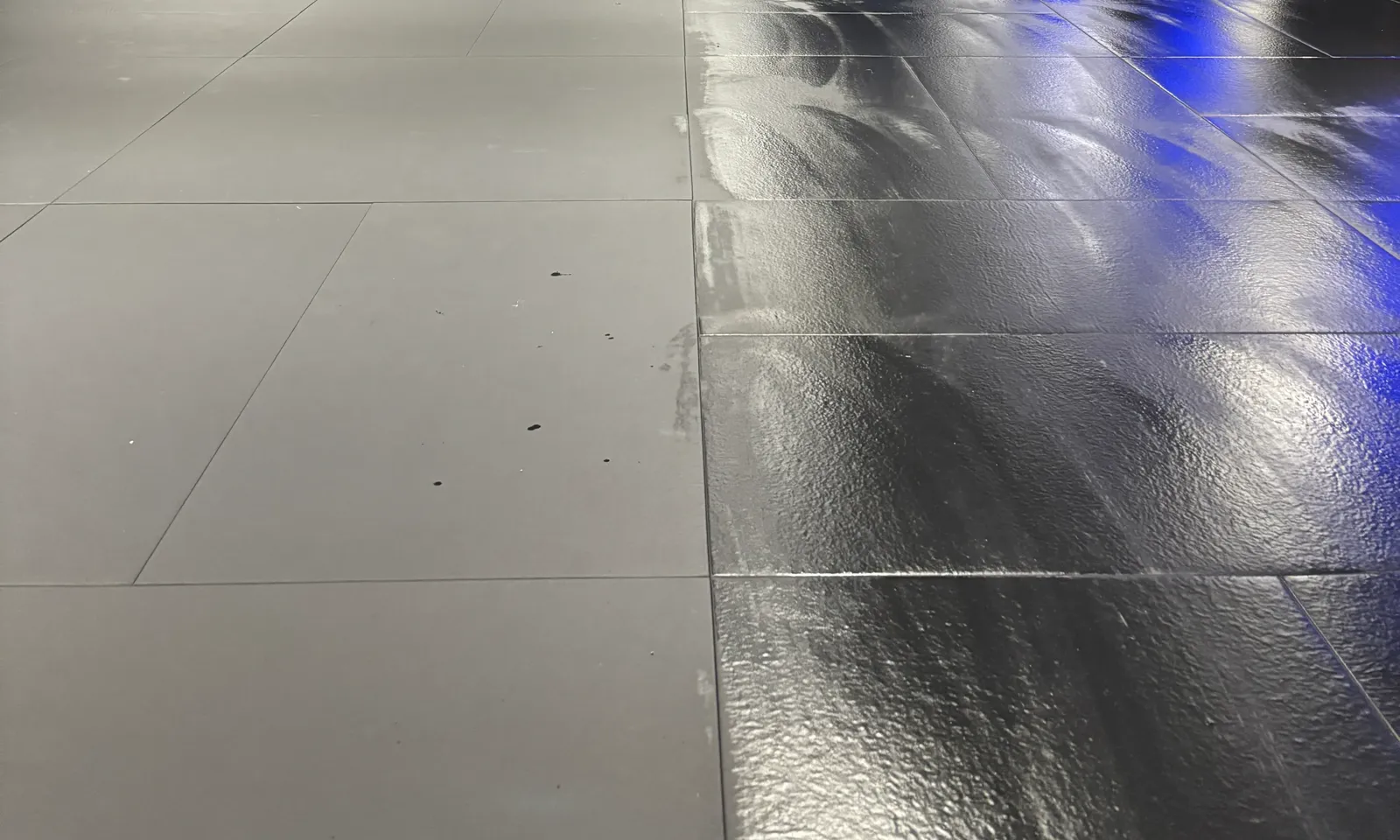 Großer Hallenboden während der Grundreinigung, die rechte Bahn ist frisch gereinigt und noch feucht