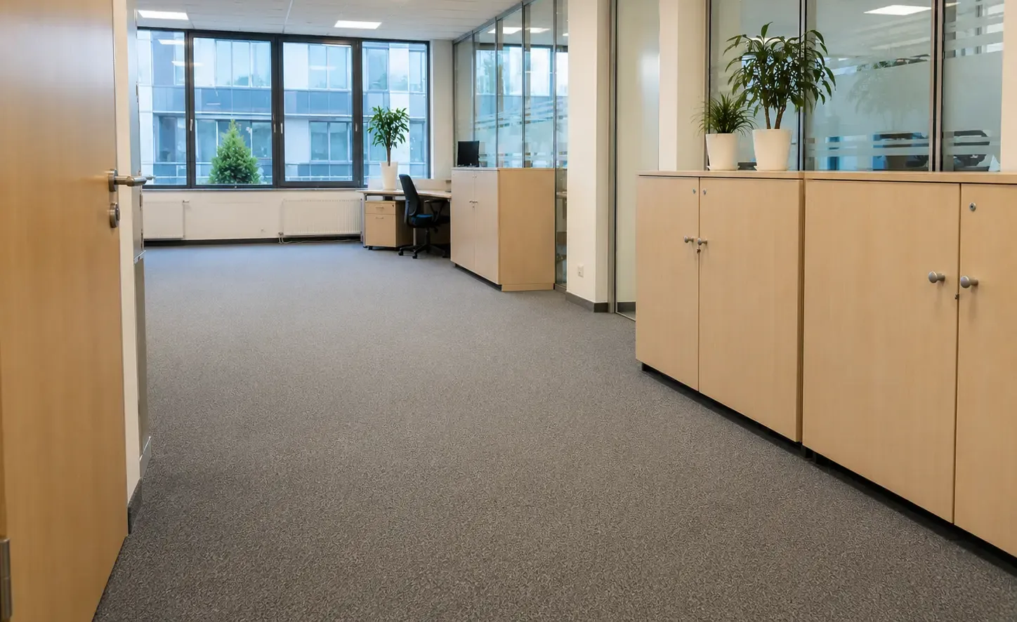 Büroraum mit frisch gereinigtem grauem Teppichboden, Aktenschränken und Fensterfront
