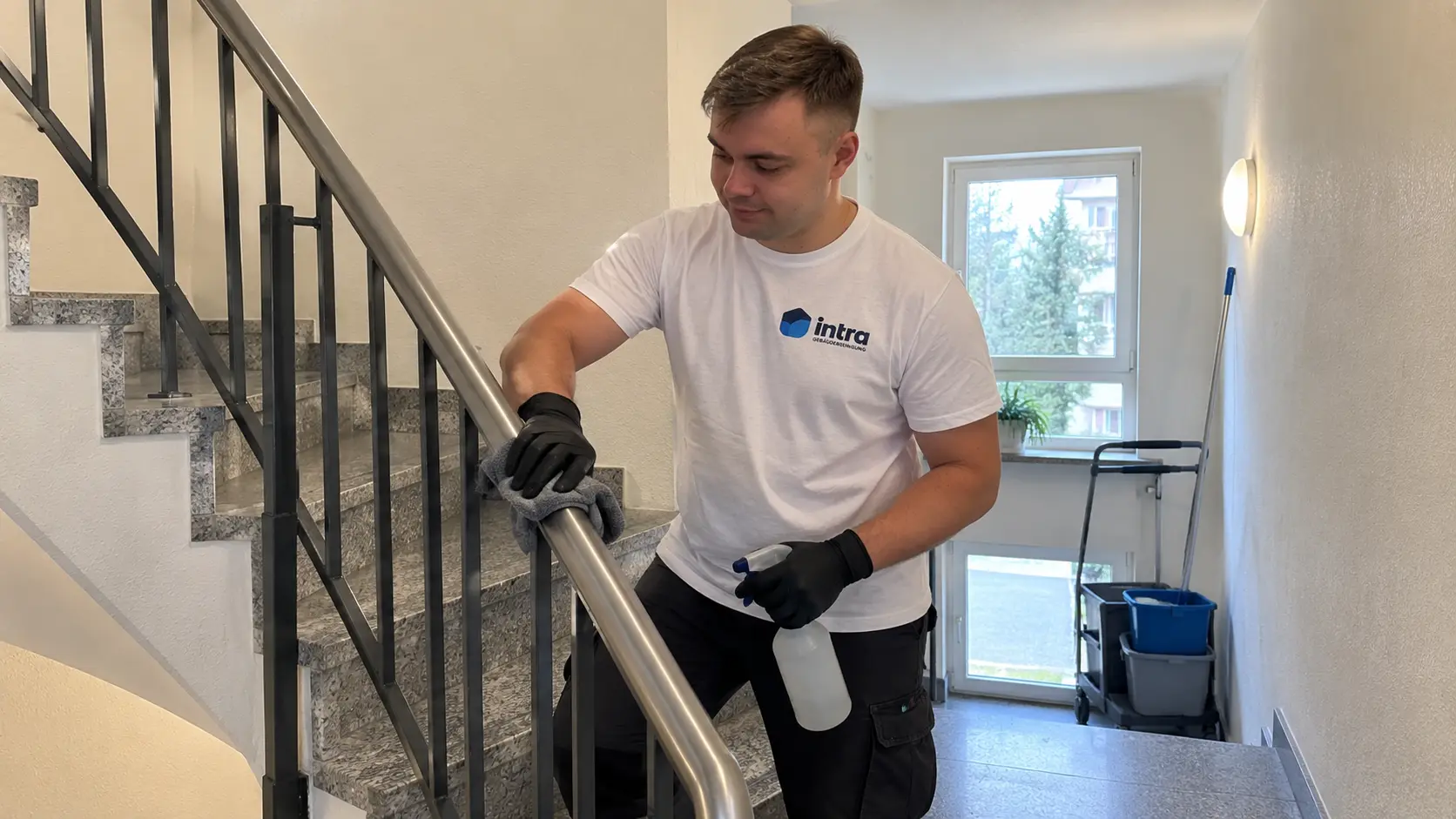 Mitarbeiter reinigt den Handlauf im Treppenhaus einer Wohnanlage in Soest